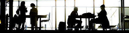 Silhouettes of people against a big window.