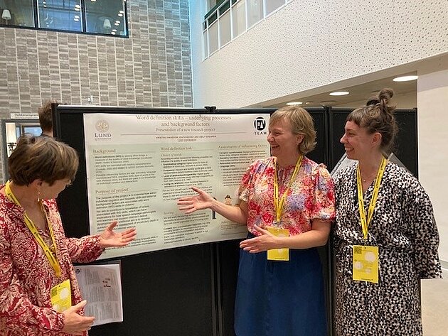 The three researchers in Project 1 look at their EdLing poster in the presentation hall