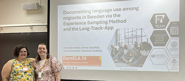 Henriette Arndt And Emma Geraerds are pictured to the left of the screen projecting the title slide of their presentation