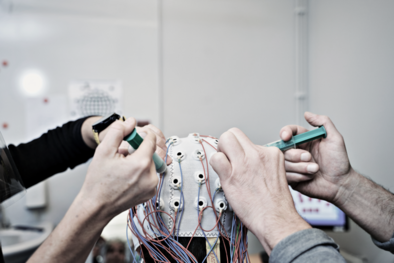 Two hands are adjusting the gel in an EEG cap